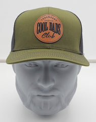 Green cap with leather patch on a mannequin head against a white background
