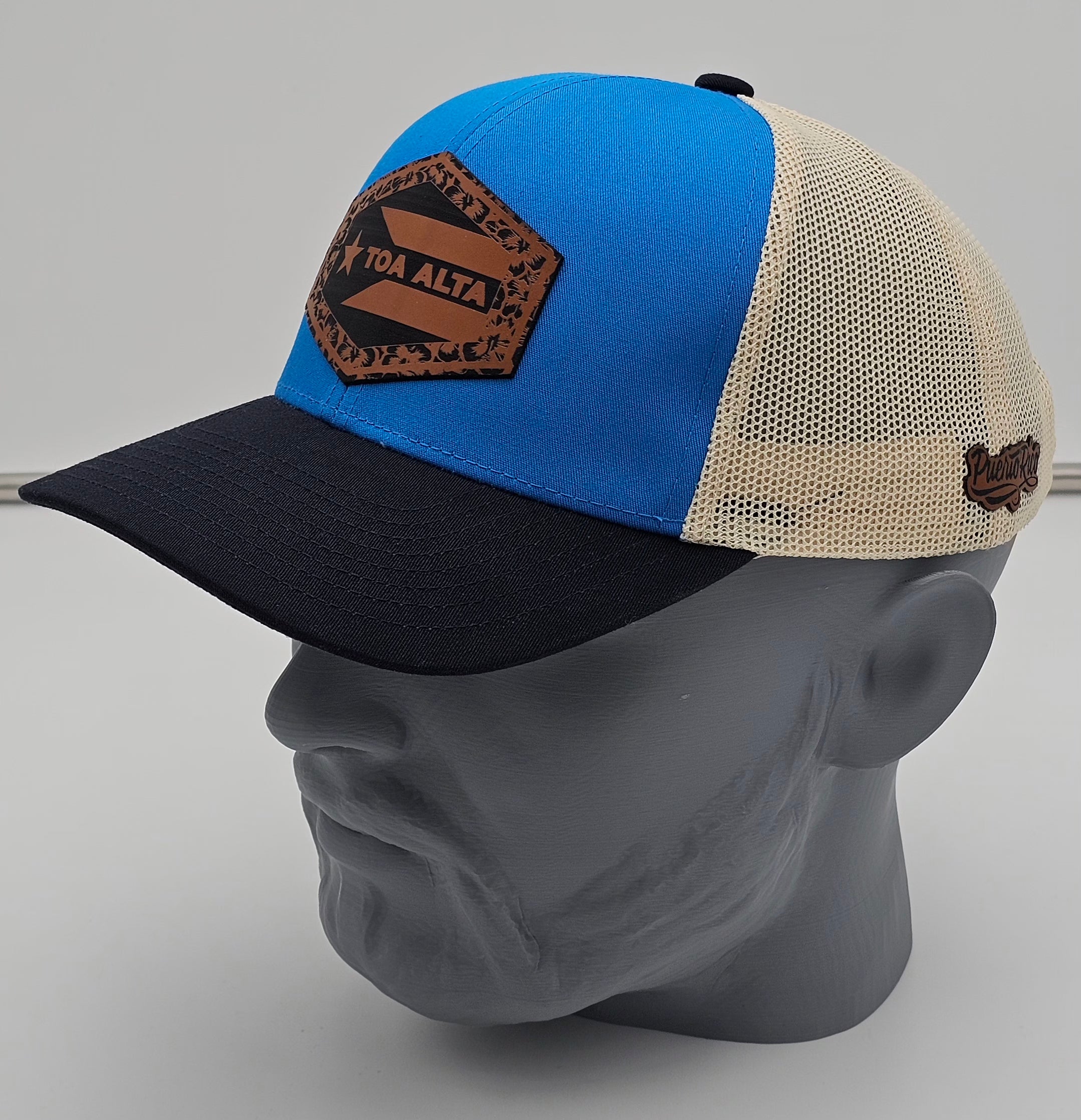 Blue and black cap with a brown patch on a gray mannequin head